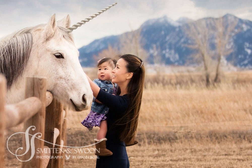 white unicorn leaning in toward mom holding her baby girl