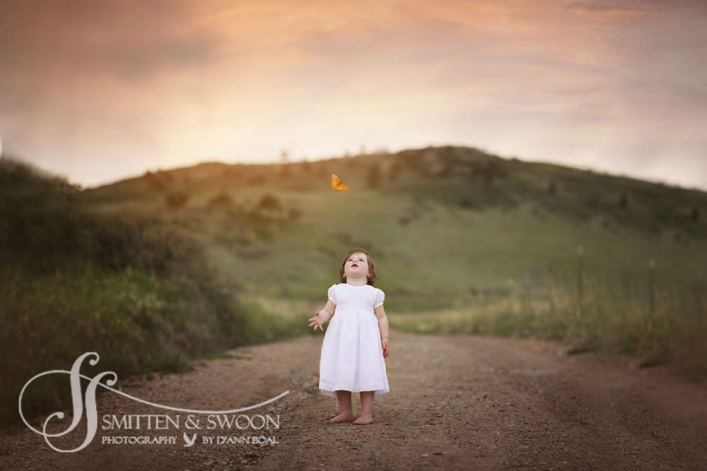 girl in white dress looking up at a monarch butterfly {boulder baby photographer}