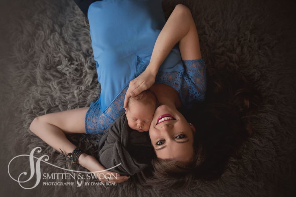 mother laying on her back looking up holding her newborn son {boulder newborn photographer}