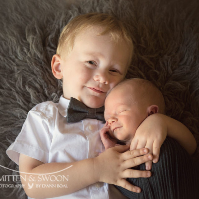 brother holding newborn baby smiling {boulder newborn photographer}