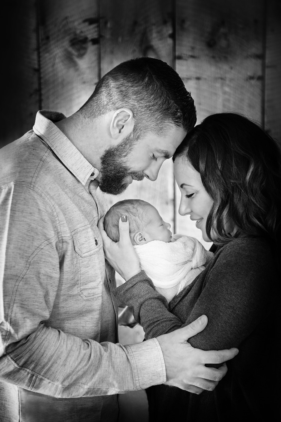 family of three holding newborn baby smiling at him - boulder photographer