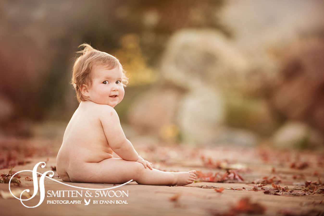 naked baby sitting in the fall leaves