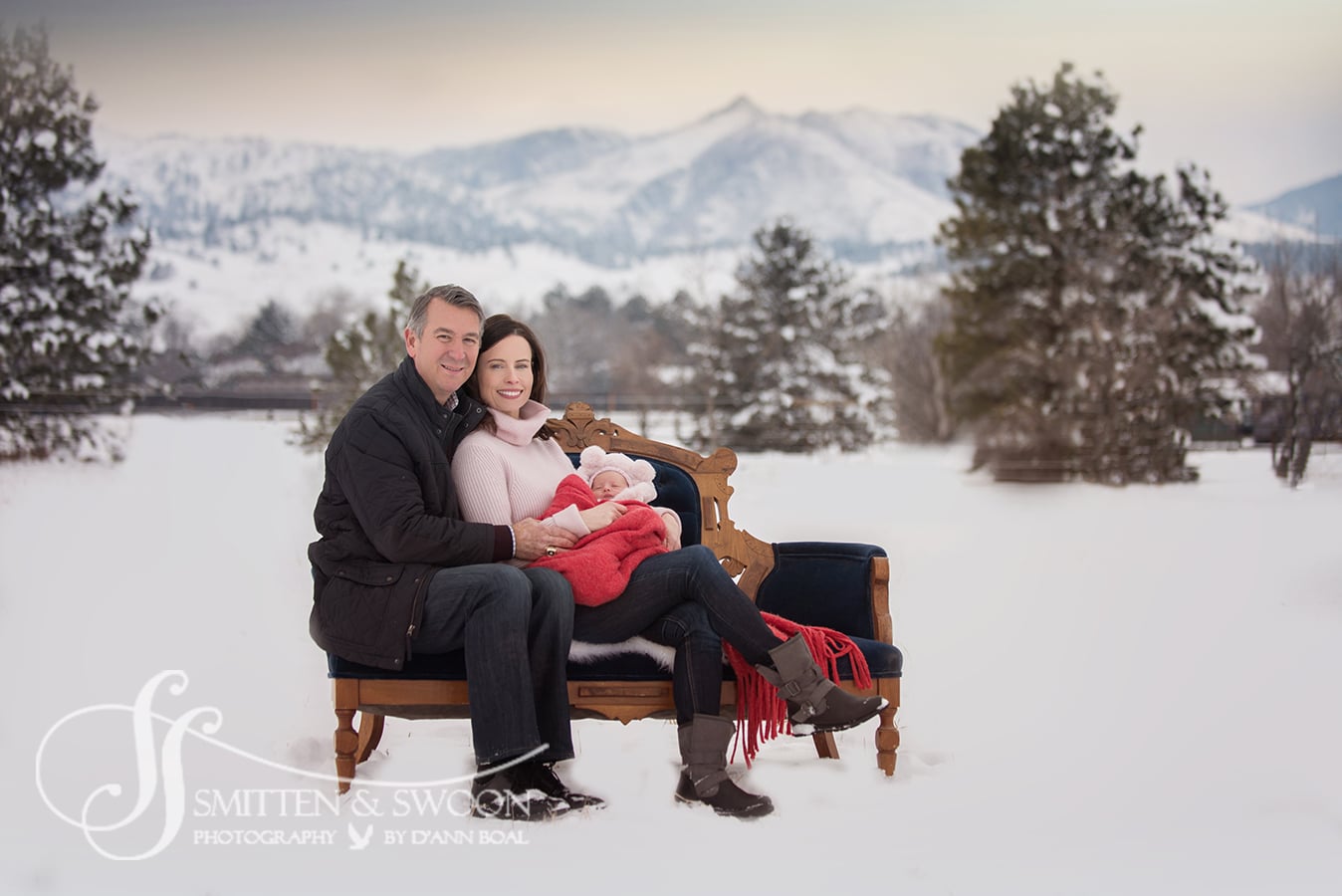 family of three sitting on couch outside with snowy mountains boulder portrait photographer