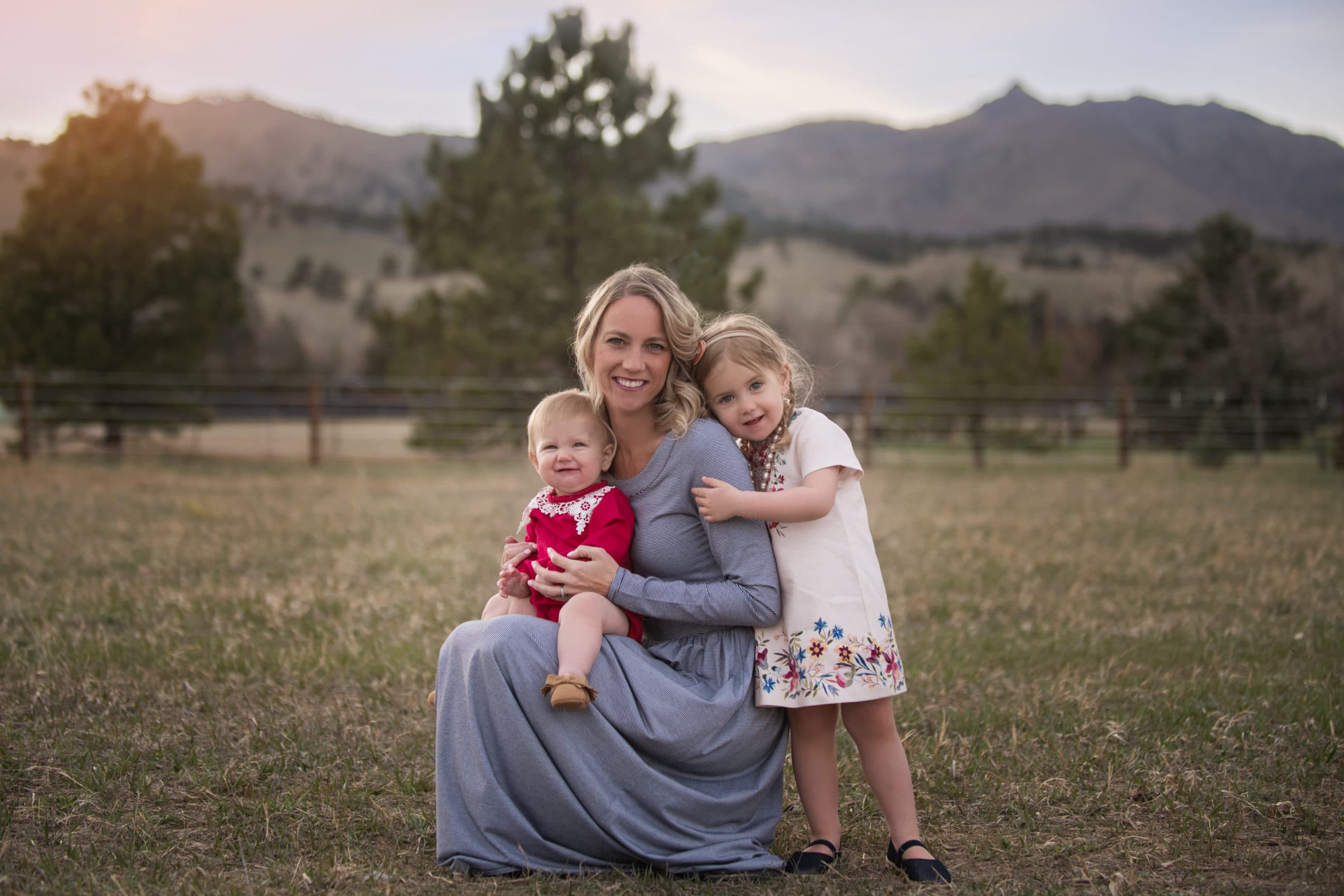 mom in field with her two daughters at sunset with mountain views - boulder family photographer