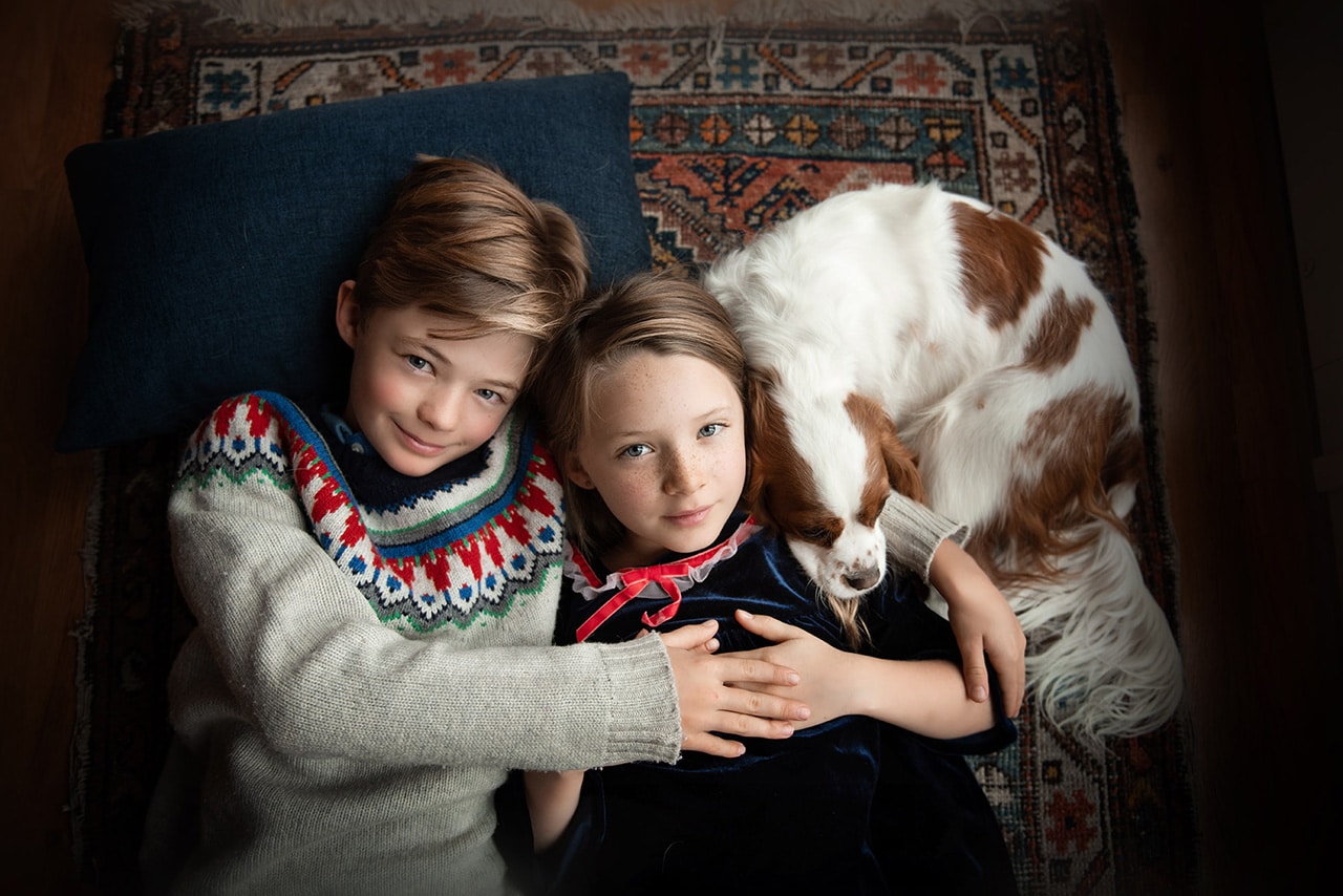 children laying hugging with King Charles cavalier puppy curled up (boulder photographer)