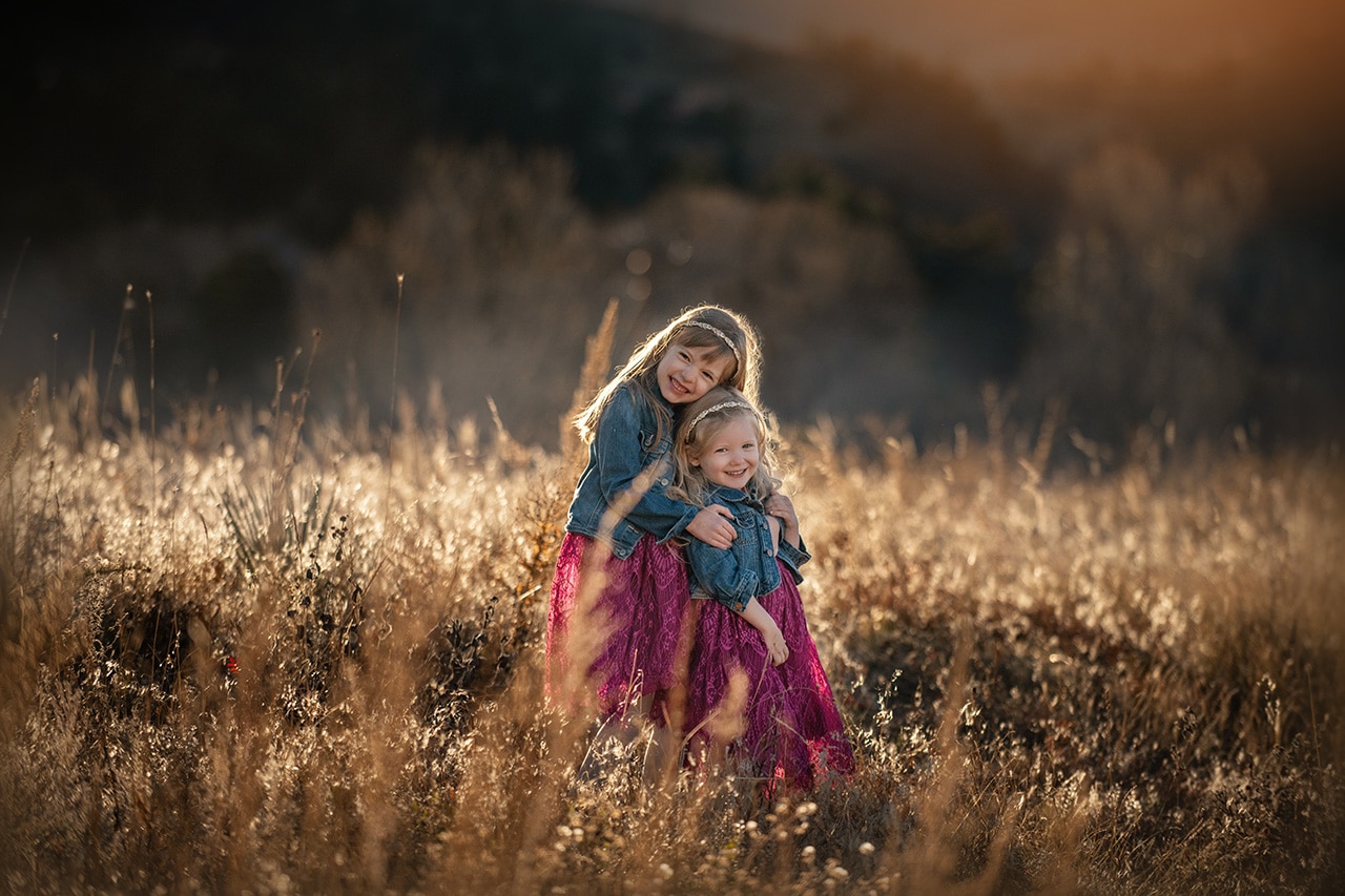 sisters hugging in golden field at sunset (boulder photographer)