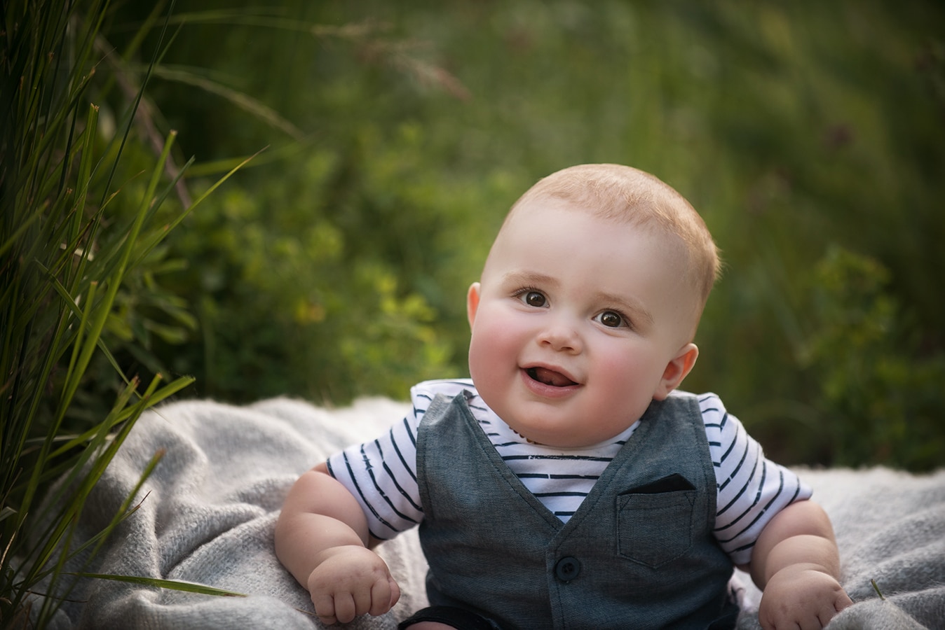 six month boy in vest in garden smiling - boulder newborn photographer