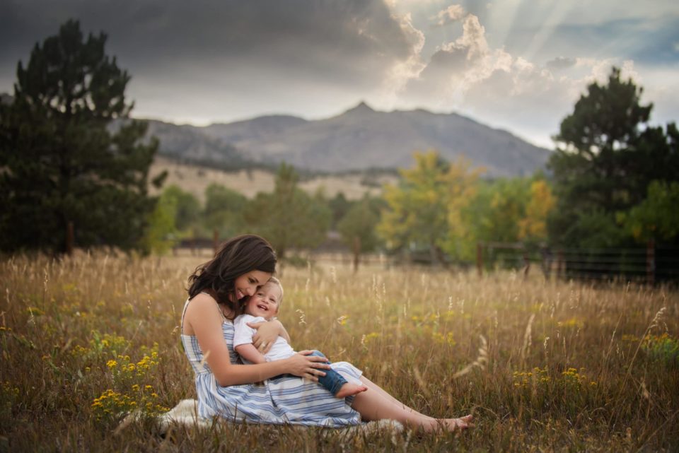 mom and baby boy snuggling in field - boulder family photographer