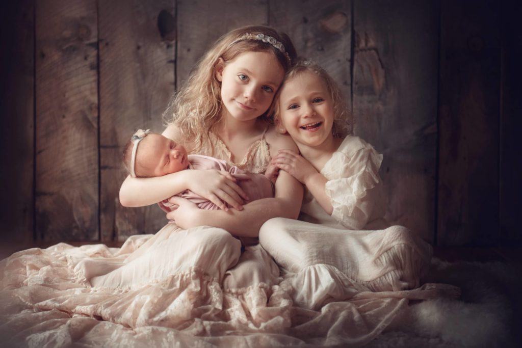 sisters holding newborn baby sister wearing lace dresses - boulder newborn photographer