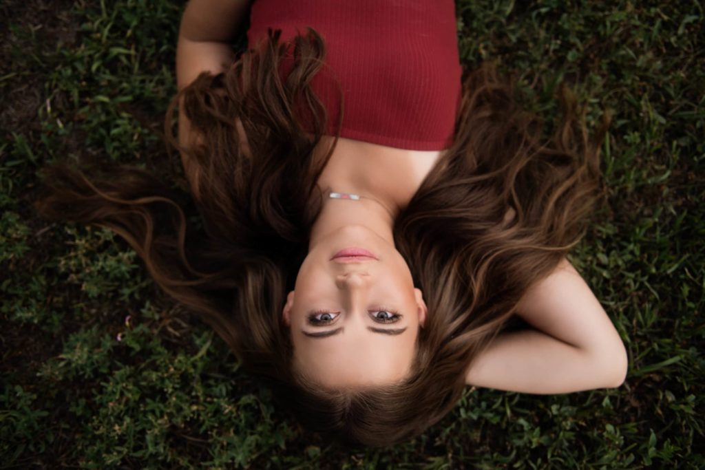 senior girl laying in grass with red shirt - Boulder photographer