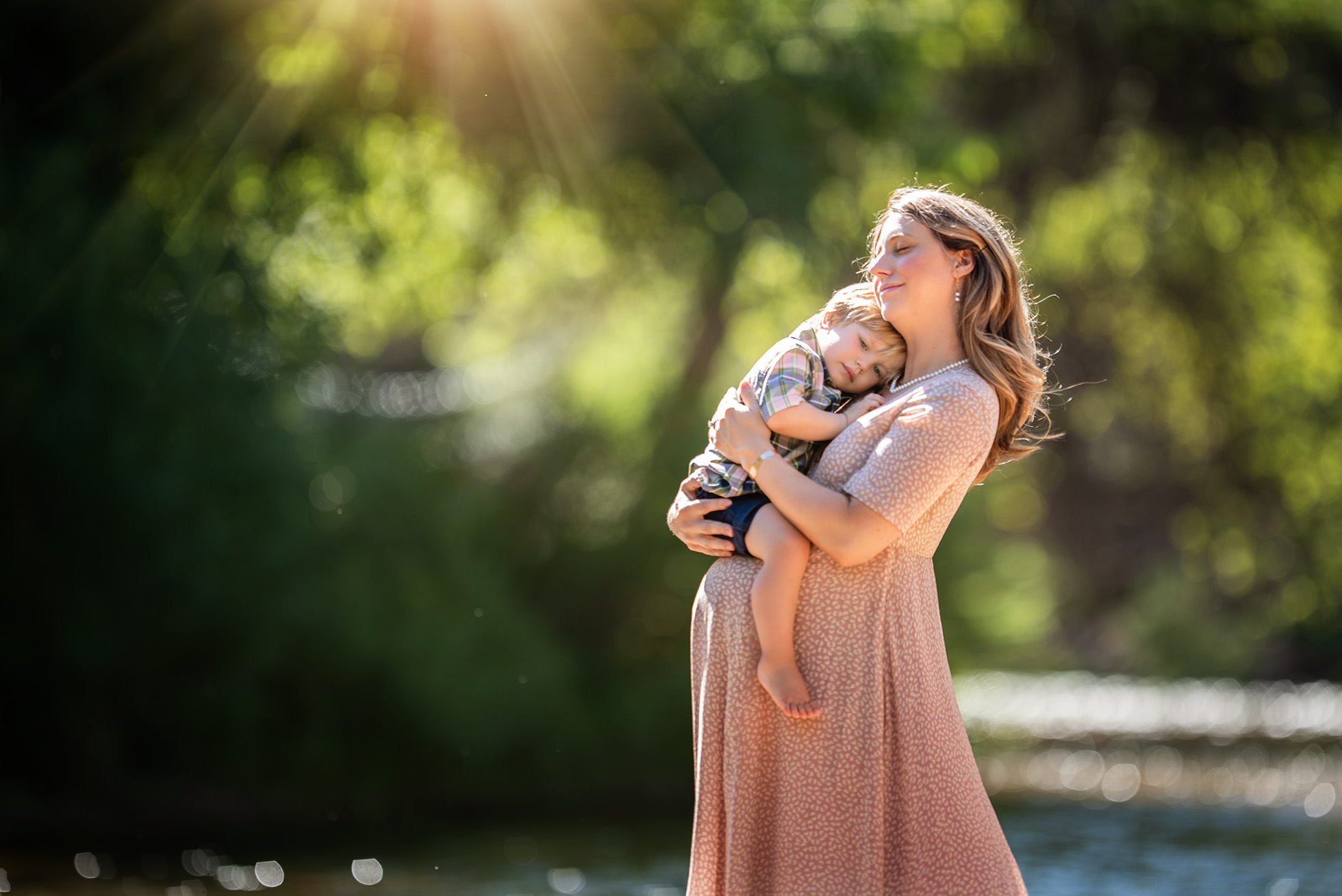 pregnant mother holding baby boy near river Boulder newborn child & family photographer | the experience