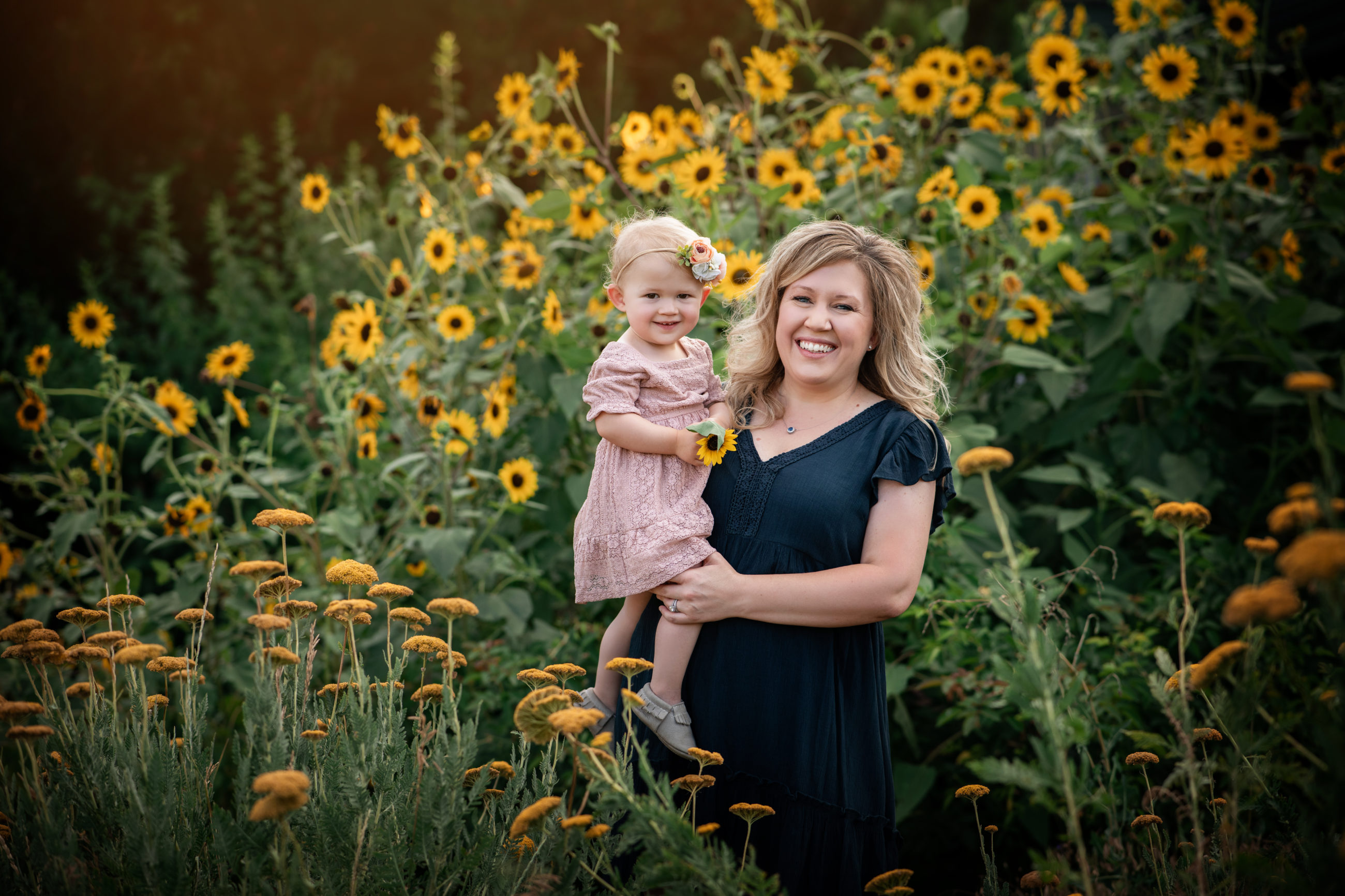 mom holding baby girl in sunflowers Mother daughter photo session | boulder family photographer