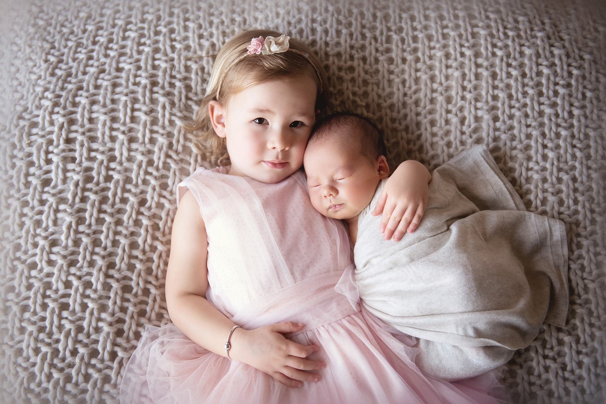 best photographer in boulder - big sister holding newborn baby brother pink and white